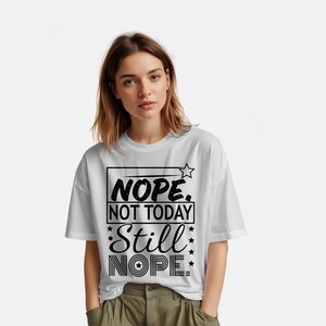 May include: White t-shirt with the text "Nope. Not Today. Still Nope." in black. The shirt has a relaxed fit and short sleeves. The text is in a bold, stylized font with star accents.