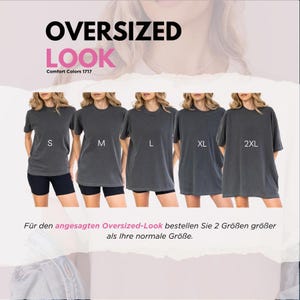 May include: A display of oversized Comfort Colors 1717 t-shirts in sizes S, M, L, XL, and 2XL. The shirts are a dark gray color. The text "OVERSIZED LOOK" is at the top of the image, with additional text below the shirts in German.