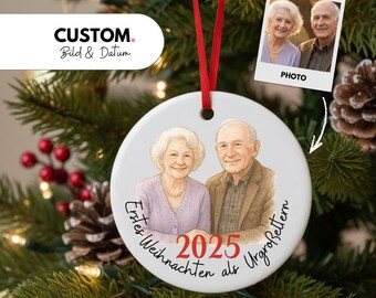 Könnte beinhalten: Runder Weihnachtsschmuck mit gemaltem Porträt eines älteren Ehepaares, dem Jahr "2025" und deutschem Text. Ein kleines Foto des Paares ist ebenfalls enthalten. Der Schmuck hängt an einem roten Band an einem Weihnachtsbaum.