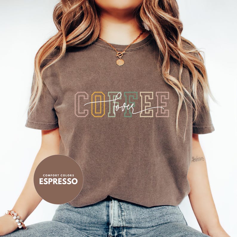 May include: Espresso-colored t-shirt with the word "COFFEE" in a retro font, with "lover" written in cursive. The shirt is a Comfort Colors brand.