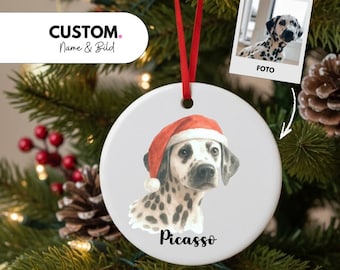 May include: A white ceramic Christmas ornament featuring a Dalmatian dog wearing a Santa hat. The dog's name, "Picasso," is written below the image. The ornament hangs from a red ribbon and has the text "CUSTOM. Name & Bild" on the left.