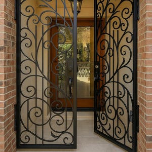 Puede incluir: Puerta de entrada de hierro forjado negro con un diseño decorativo de volutas. La puerta está abierta, revelando un vistazo del interior con una puerta de madera y un exterior de ladrillo. El diseño presenta patrones arremolinados y barras verticales.