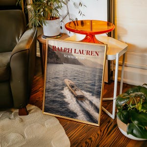 Luxury yacht speeding across the ocean at sunset with coastal mountains in the background, styled as elegant coastal lifestyle wall art.