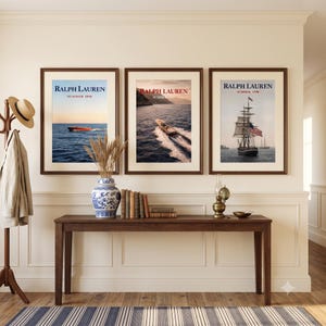 May include: Three framed wall art prints featuring Ralph Lauren Summer 1998 nautical imagery, including a red motorboat, a wooden boat on water, and a large sailing ship with an American flag, displayed above a long wooden console table.