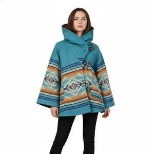 May include: A teal hooded coat with a Southwestern-inspired pattern in shades of brown, orange, and blue. The coat features a toggle closure and a wide, flowing design. The model is wearing black pants and boots.