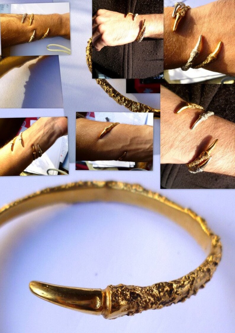May include: A gold bangle bracelet with a textured surface and two claw-like ends. The bracelet is open and has a rounded shape.