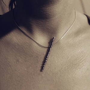 Puede incluir: Un collar de plata con un colgante de flauta. La flauta est&aacute; hecha de metal y tiene un dise&ntilde;o detallado.