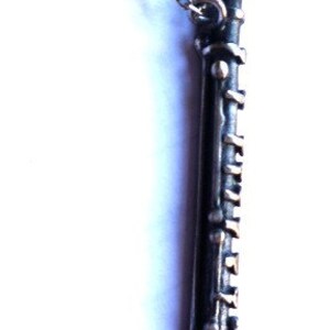Puede incluir: Un collar de cadena de plata con un colgante de plata con forma de clarinete. El clarinete est&aacute; detallado con llaves de plata y una boquilla de plata.