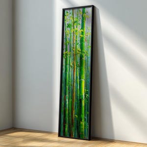 May include: Vertical framed artwork depicting a bamboo forest. The painting features vibrant green bamboo stalks with yellow-green leaves, set against a soft, blurred background. The artwork is encased in a black frame, leaning against a white wall.
