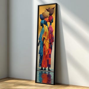 Puede incluir: Una impresión artística enmarcada que representa a tres mujeres con coloridas túnicas, cada una llevando una cesta en la cabeza. La obra presenta una vibrante paleta de azules, naranjas y rojos sobre un fondo amarillo, con un reflejo en la parte inferior.