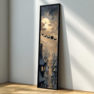 Peut inclure: Une impression d'art verticale encadrée représentant une scène hivernale avec une pleine lune et le traîneau du Père Noël. L'œuvre présente une silhouette du Père Noël et des rennes volant au-dessus d'une ville enneigée avec des fenêtres éclairées. Le cadre est noir.