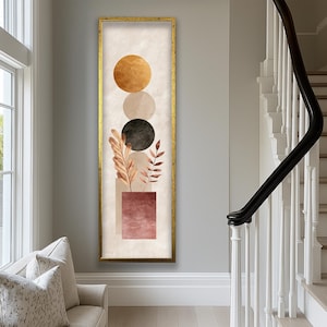 Peut inclure: Impression d'art abstrait vertical dans un cadre doré. L'œuvre présente trois cercles superposés en or, beige et noir, avec un carré couleur terre cuite en bas. Des feuilles et des tiges brunes sont disposées dans le carré.