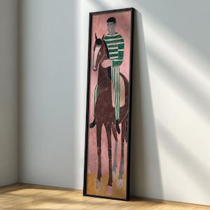 Puede incluir: Una pintura enmarcada representa a una persona a caballo. El jinete viste una camisa a rayas verdes y blancas y está montado sobre un caballo marrón. El fondo es rosa y el marco es negro. La obra de arte se exhibe contra una pared blanca y un suelo de madera.