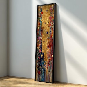 Puede incluir: Una impresión artística vertical enmarcada con un borde negro. La obra presenta un fondo dorado con coloridos patrones florales y geométricos en rojo, azul y amarillo. La pieza se apoya contra una pared blanca sobre un suelo de madera.