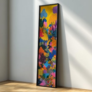 May include: A colorful framed artwork featuring a vibrant forest scene. The painting showcases trees with blue, orange, and purple foliage against a yellow sky. The artwork is in a black frame and leans against a white wall.