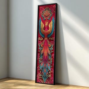 May include: Framed artwork depicting a phoenix. The artwork has a red background with a detailed phoenix in gold, blue, and red. The phoenix is shown with outstretched wings and a long, flowing tail. The artwork is encased in a black frame.