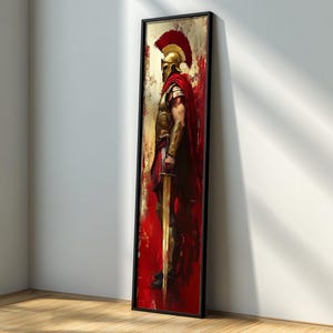 May include: A framed vertical artwork depicts a Spartan warrior in profile. The warrior wears a gold helmet with a red plume, a red cape, and gold armor. The background is a blend of red and gold hues, with a black frame.