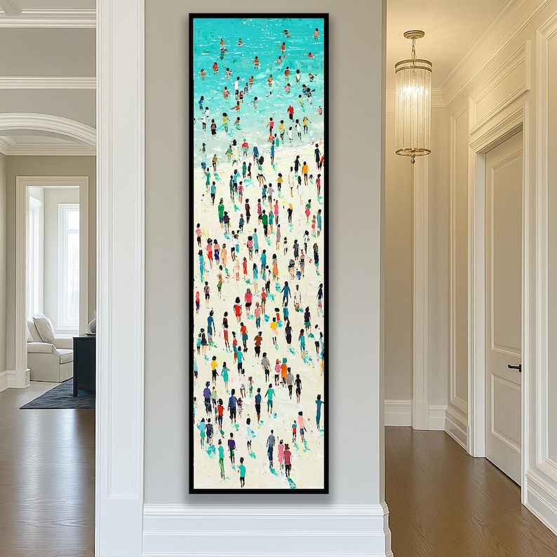 May include: Vertical framed art print depicting a beach scene with numerous figures. The top portion shows a turquoise ocean with people swimming. The lower section features a sandy beach with a crowd of people in various colorful outfits. The artwork is framed in black.