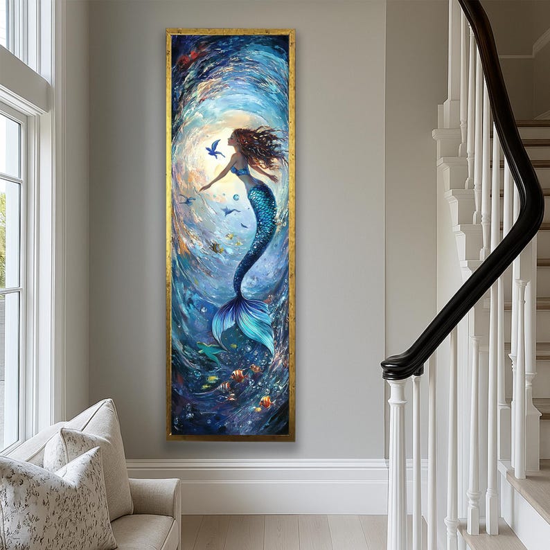 May include: A vertical framed painting of a mermaid in a swirling blue ocean. The mermaid has long brown hair and a blue tail. The painting has a gold frame and is displayed on a gray wall.
