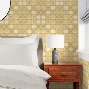 May include: A bedroom scene featuring a bed with white bedding, a wooden nightstand, and a lamp with a white shade. The lamp has a gray marble base. The wallpaper has a yellow and white plaid pattern.