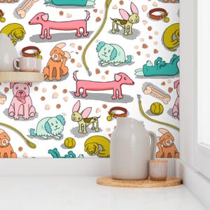 May include: A white background is covered with colorful cartoon dogs in various poses. The dogs are pink, orange, green, and brown. There are also dog collars, bones, and tennis balls scattered across the surface.