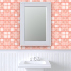 Pu&ograve; includere: Uno specchio con cornice bianca &egrave; montato su una parete con un motivo a quadri pesca e bianco. Sotto lo specchio c'&egrave; un lavandino bianco con un rubinetto cromato. Il muro ha un design a boiserie.
