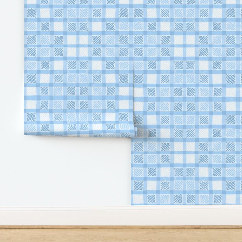 May include: A roll of blue and white checkered wallpaper. The pattern features a grid of light blue and white squares, with each square containing a textured, cross-hatched design. The wallpaper is partially unrolled, revealing the pattern against a white wall.