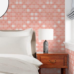 Pu&ograve; includere: Una scena di camera da letto con un letto, un comodino e una lampada. Il letto ha biancheria da letto bianca. Il comodino &egrave; in legno. La lampada ha un paralume bianco e una base in marmo grigio. La parete &egrave; rivestita da carta da parati a quadri rosa e bianchi.