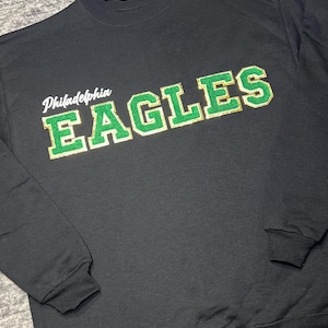 May include: Black sweatshirt with a green and gold "Philadelphia Eagles" graphic.