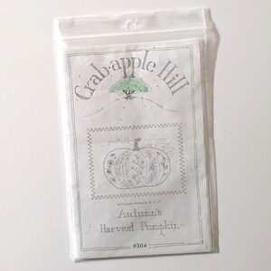 May include: A clear plastic bag containing a white paper with the text "Crabapple Hill" and a drawing of a tree. The paper features a pumpkin design with the text "Autumn's Harvest Pumpkin" and the size "9 x 13".