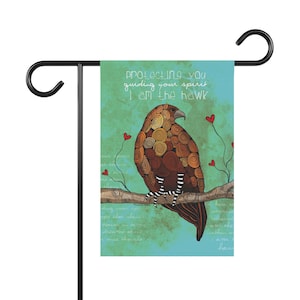 May include: A teal blue garden flag with a brown and white hawk perched on a branch. The hawk is surrounded by red hearts and the text "protecting you guiding your spirit I am the hawk".