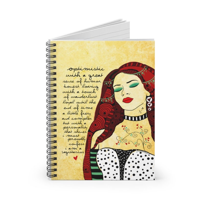 May include: A spiral bound notebook with a vintage-style cover featuring a colorful illustration of a woman with red hair and a quote about Sagittarius. The quote reads: "optimistic with a great sense of humor honest loving with a touch of wanderlust loyal until the end of time a little fiery and complex but with a personality that shines i must proudly confess i am a Sagittarius"