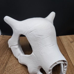 Puede incluir: Una m&aacute;scara de calavera blanca sin pintar con cuernos y una superficie texturizada. La m&aacute;scara tiene cuencas oculares grandes y una apariencia detallada de hueso. La m&aacute;scara es probablemente para cosplay o disfraces.