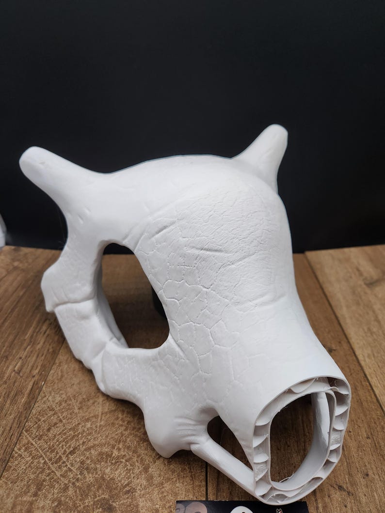 Puede incluir: Una m&aacute;scara de calavera blanca sin pintar con cuernos y una superficie texturizada. La m&aacute;scara tiene cuencas oculares grandes y una apariencia detallada de hueso. La m&aacute;scara es probablemente para cosplay o disfraces.
