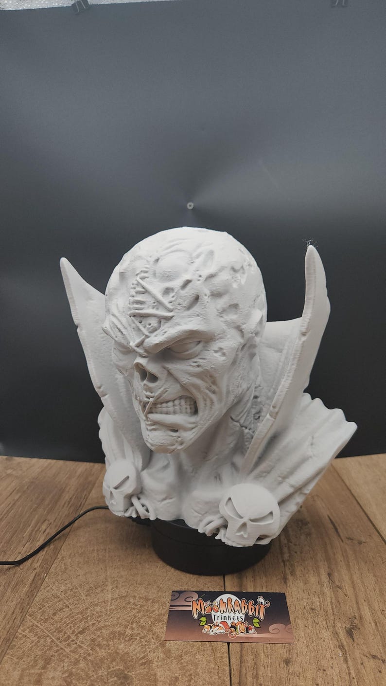 Puede incluir: Una taza de cer&aacute;mica blanca con asa negra y el texto "But First, Coffee" en negrita negra. La taza se encuentra sobre un fondo borroso, sugiriendo un ambiente acogedor.