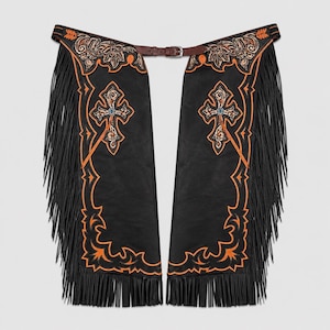 Puede incluir: Chaps de cuero negro con cruces y diseños florales bordados en naranja. Los chaps tienen largas flecos negros y un cinturón de cuero marrón con hebilla. Prenda de estilo western.