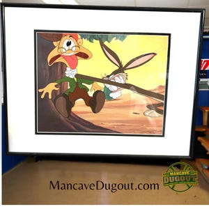 Puede incluir: Una ilustración de dibujos animados enmarcada de un personaje de Bugs Bunny sosteniendo un palo y un personaje con una nariz grande y gafas que huye. El fondo es una escena de desierto con un árbol.