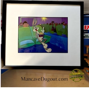 Puede incluir: Una ilustración de dibujos animados enmarcada de Bugs Bunny sentado en un asiento de cine, comiendo palomitas de maíz. El fondo muestra un cine con otros personajes de dibujos animados en la audiencia.
