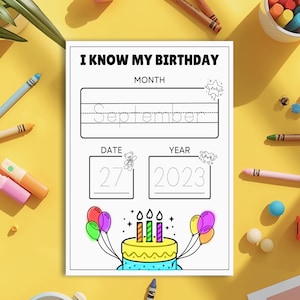 May include: A black and white birthday worksheet with the text "I KNOW MY BIRTHDAY". The worksheet has spaces for the month, date, and year. A colourful birthday cake with candles and balloons is illustrated at the bottom. Crayons and markers surround the worksheet.