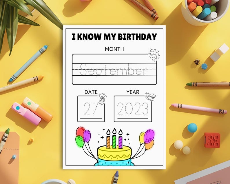 May include: A black and white birthday worksheet with the text "I KNOW MY BIRTHDAY". The worksheet has spaces for the month, date, and year. A colourful birthday cake with candles and balloons is illustrated at the bottom. Crayons and markers surround the worksheet.