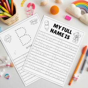 May include: Two white worksheets with black text and illustrations for learning. One sheet says "B IS FOR" with a dotted "B". The other says "MY FULL NAME IS" and includes the name "Oliver Brown" for tracing. Colour pencils and pens are nearby.