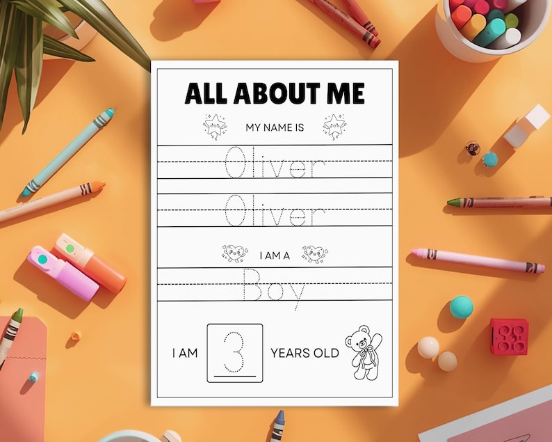 May include: A white "All About Me" worksheet with the name "Oliver" and the word "Boy" printed on it. The worksheet also includes the number "3" and the words "Years Old". The worksheet is surrounded by colourful crayons and markers.