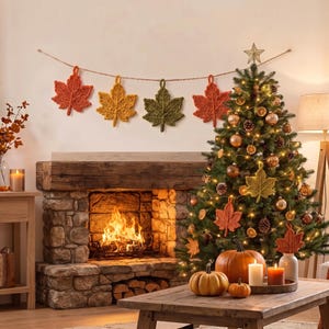 May include: A festive holiday scene featuring a string of four crocheted maple leaf ornaments in orange, yellow, and green hanging above a stone fireplace. A decorated Christmas tree stands nearby, adorned with lights, ornaments, and matching leaf accents.