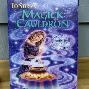 May include: A paperback book titled To Stir A Magick Cauldron: A Witch's Guide to Casting and Conjuring by Silver RavenWolf. The cover features a person with curly hair standing behind a cauldron with swirling purple and blue cosmic energy.