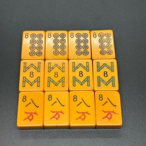May include: A collection of twelve orange Mahjong tiles arranged in three rows. The tiles feature various symbols, including circles, bamboo stalks, and Chinese characters. Each tile displays the number "8".