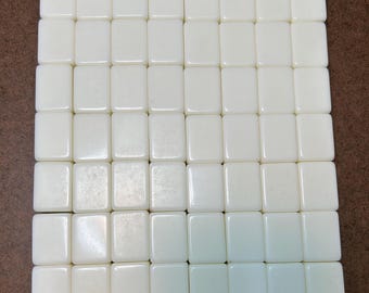 May include: A grid of forty-nine rectangular, off-white mahjong tiles arranged in seven rows and seven columns. Each tile features a smooth, blank, and uniform surface with rounded edges, presenting a consistent and clean appearance.