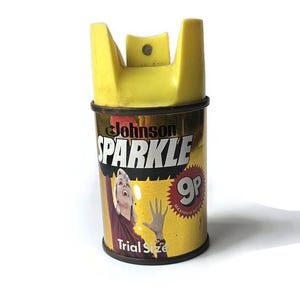 May include: A vintage Johnson Sparkle cleaning product can with a yellow top and a gold and yellow label. The label features the word "SPARKLE", a woman, and the words "Trial Size".