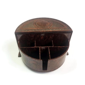 May include: A semi-circular desk organizer with a dark brown marbled finish. The unit features a flat back section with a circular embossed detail and a front compartment divided into five distinct sections for holding various small items.