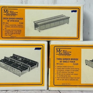 May include: Three model train bridge kits in their original packaging. The boxes are yellow and orange with black text. The boxes are labeled "Thru Girder Bridge 50 Double Track HO Scale 75-821", "Deck Girder Bridge 30 Open Deck HO Scale 75-102", and "Thru Girder Bridge 50 Single Track HO Scale 75-520".
