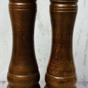 May include: Two wooden salt and pepper grinders with brass accents. The grinders have a dark brown finish with a bulbous shape and a brass top and bottom. The grinders are standing upright.